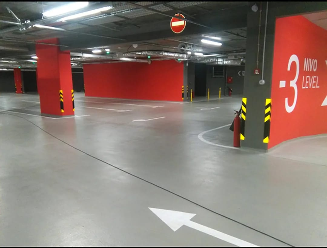 Parking garage level marked with large white wayfinding graphics and yellow and black hazard chevrons on a column