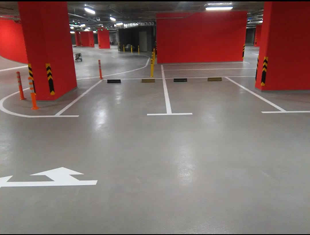 Parking garage bays with crisp white stall lines, T-marks, wheel stops and orange delineator posts