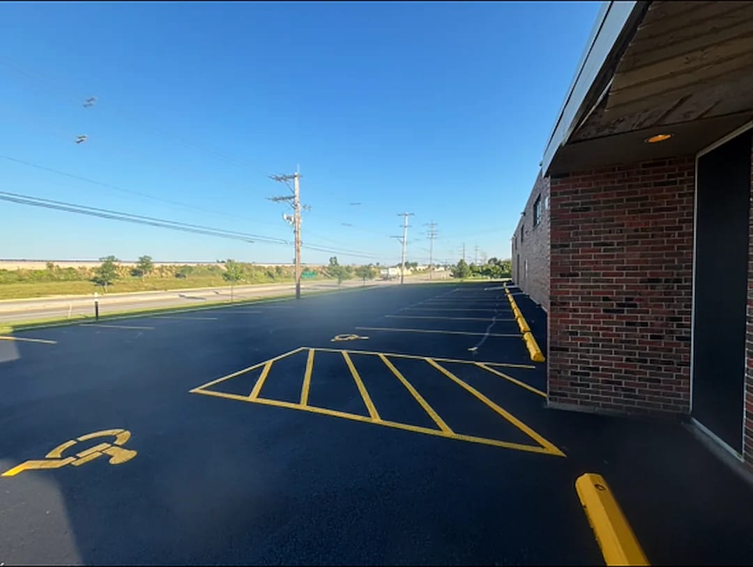 Freshly striped asphalt parking lot with yellow stall lines, a hatched no-parking zone and a painted ADA symbol